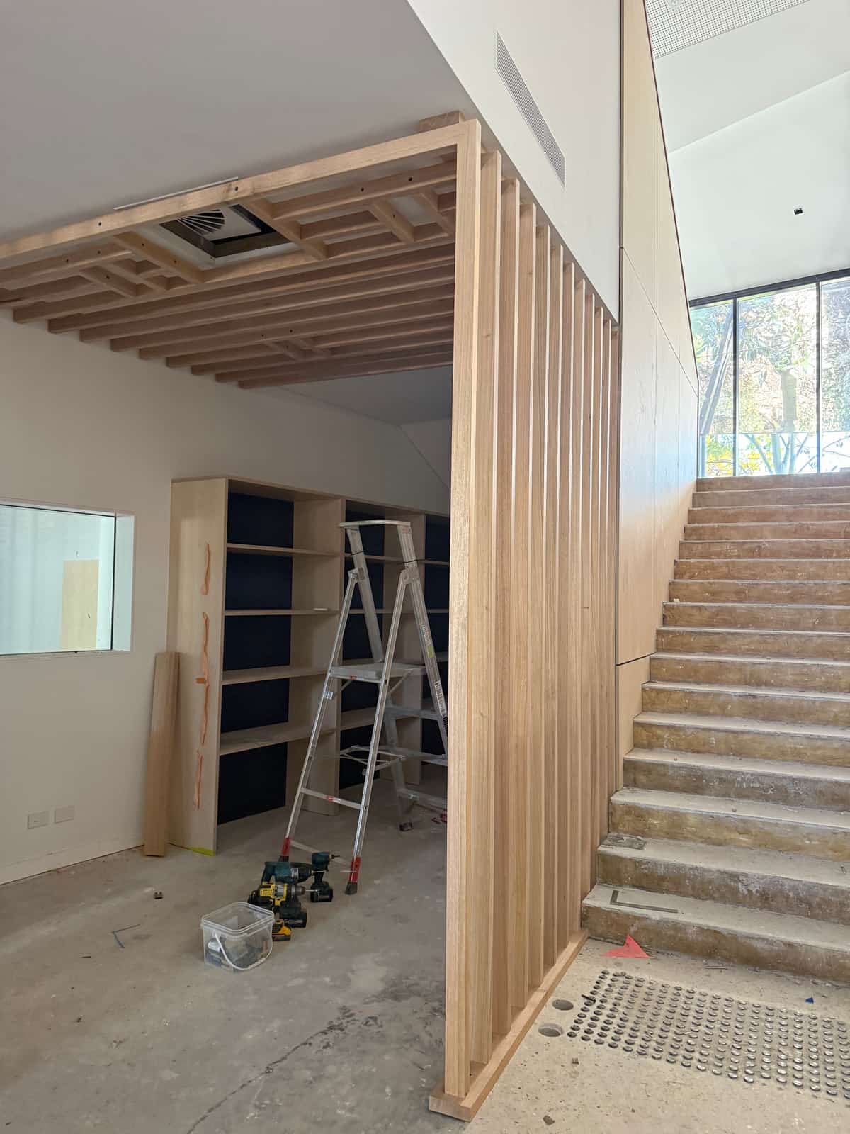 Timber batten screen and battened ceiling with built-in shelving, carpentry by Hogan Projects